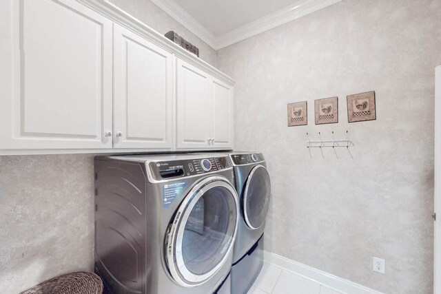 laundry room with cabinets, washer and clothes dryer, crown molding, and light tile patterned flooring