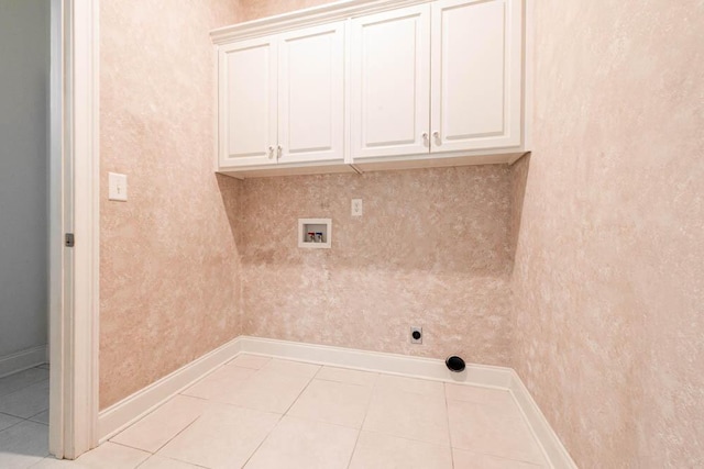 washroom with tile patterned flooring, hookup for a washing machine, cabinet space, and baseboards