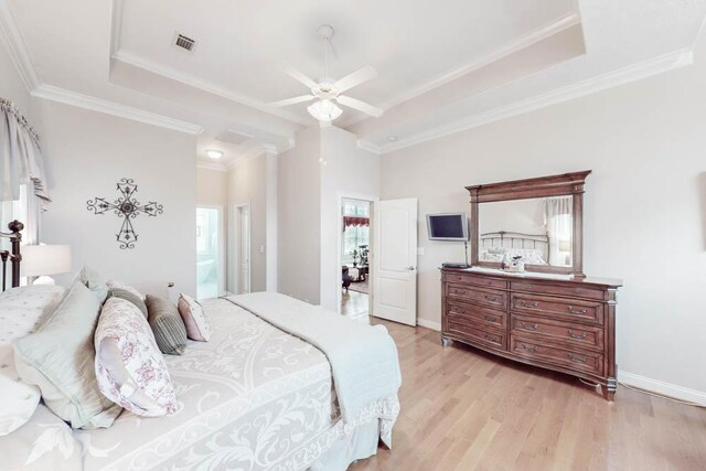 bedroom with connected bathroom, ceiling fan, crown molding, a tray ceiling, and light wood-type flooring