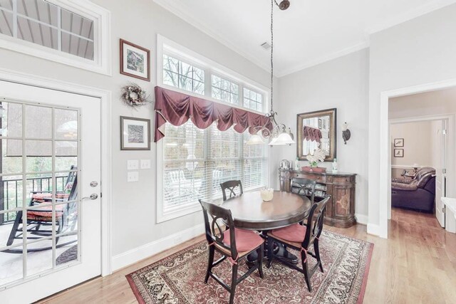 dining space featuring light hardwood / wood-style flooring, a towering ceiling, and ornamental molding