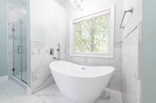 full bath with marble finish floor, a shower stall, and tile walls