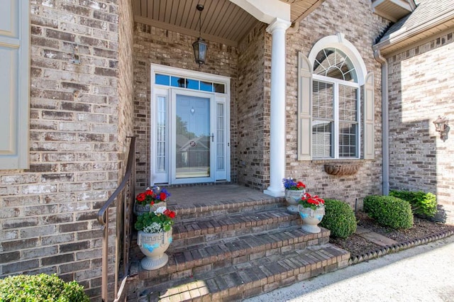 property entrance with a porch and brick siding