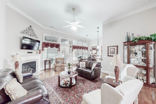 living room with a fireplace, light wood-type flooring, ceiling fan, and ornamental molding