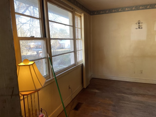 empty room featuring a wealth of natural light and dark hardwood / wood-style floors