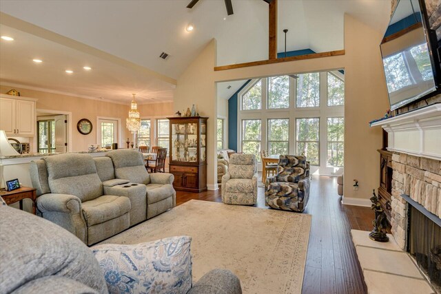 living room featuring dark wood-type flooring, high vaulted ceiling, a stone fireplace, ceiling fan, and ornamental molding