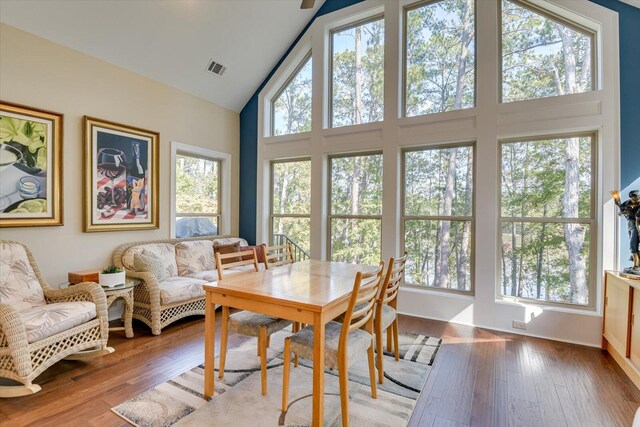 dining space with high vaulted ceiling and light wood-type flooring