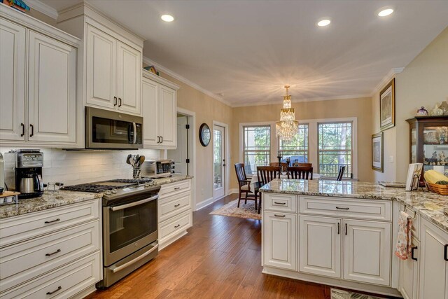 kitchen featuring hanging light fixtures, light wood-type flooring, appliances with stainless steel finishes, tasteful backsplash, and a notable chandelier