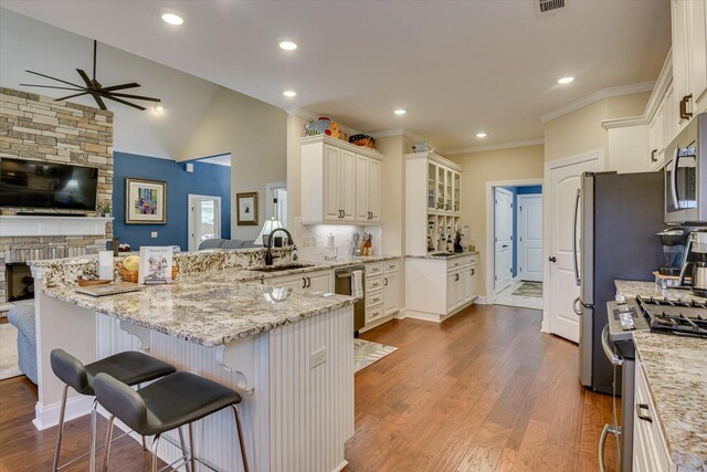 kitchen with stainless steel appliances, backsplash, kitchen peninsula, vaulted ceiling, and a kitchen bar