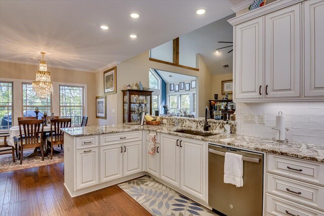 kitchen with sink, stainless steel dishwasher, kitchen peninsula, pendant lighting, and decorative backsplash