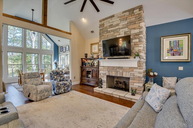 living room with a stone fireplace, ceiling fan, plenty of natural light, and high vaulted ceiling