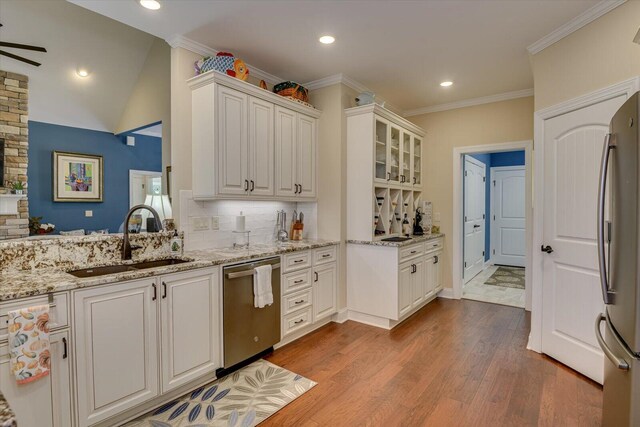 kitchen with white cabinets, stainless steel appliances, light stone countertops, and sink