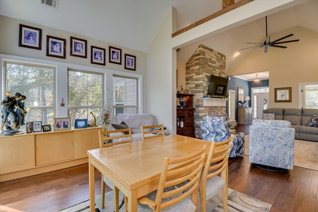 dining space featuring ceiling fan, a fireplace, high vaulted ceiling, and wood-type flooring