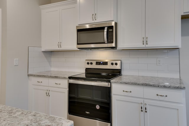 kitchen with decorative backsplash, white cabinets, stainless steel appliances, and light stone counters