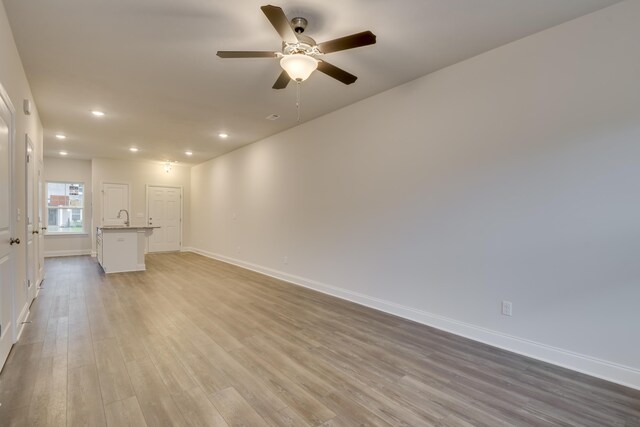 unfurnished living room featuring ceiling fan, light hardwood / wood-style floors, and sink