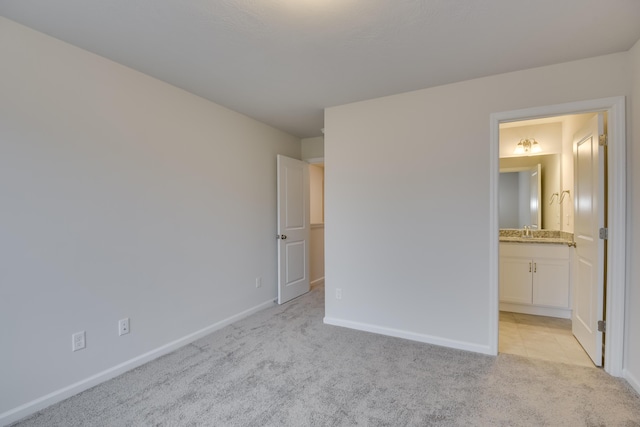 unfurnished bedroom with connected bathroom, sink, and light colored carpet