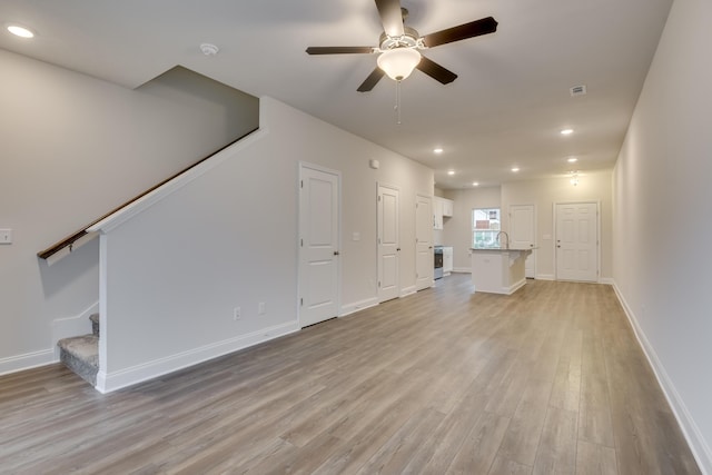 unfurnished living room with light hardwood / wood-style floors, ceiling fan, and sink