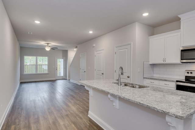 kitchen with appliances with stainless steel finishes, ceiling fan, sink, a center island with sink, and white cabinets