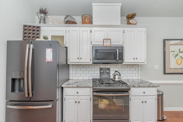 2108 Glenn Fls, Grovetown, GA 30813 - kitchen with stainless steel appliances, white cabinetry, backsplash, and light stone countertops