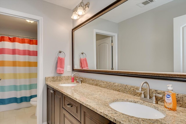 bathroom with a sink, visible vents, toilet, and double vanity