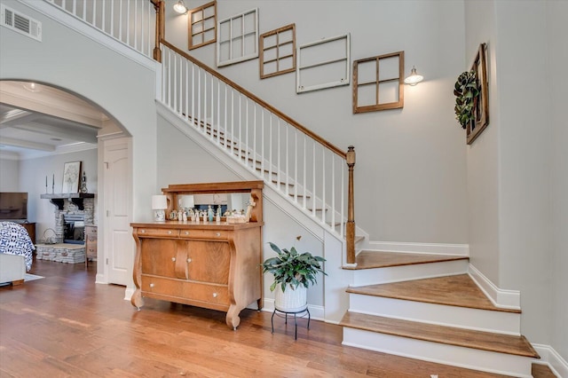 stairs with visible vents, baseboards, wood finished floors, and a towering ceiling