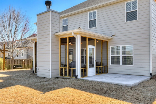 rear view of house featuring fence, roof with shingles, a chimney, a sunroom, and a patio area