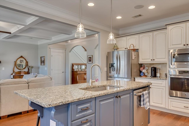 kitchen featuring visible vents, a sink, arched walkways, light wood-style floors, and appliances with stainless steel finishes