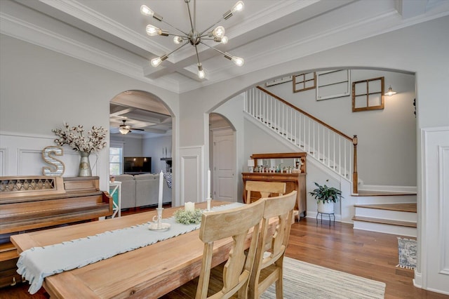 dining area with beamed ceiling, coffered ceiling, wood finished floors, stairway, and arched walkways