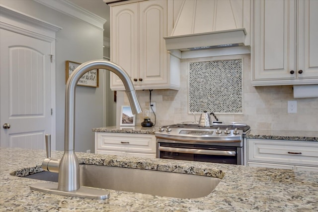 kitchen featuring ornamental molding, custom range hood, light stone counters, gas stove, and decorative backsplash