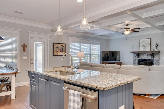 kitchen with visible vents, a sink, light wood-style floors, a stone fireplace, and dishwasher