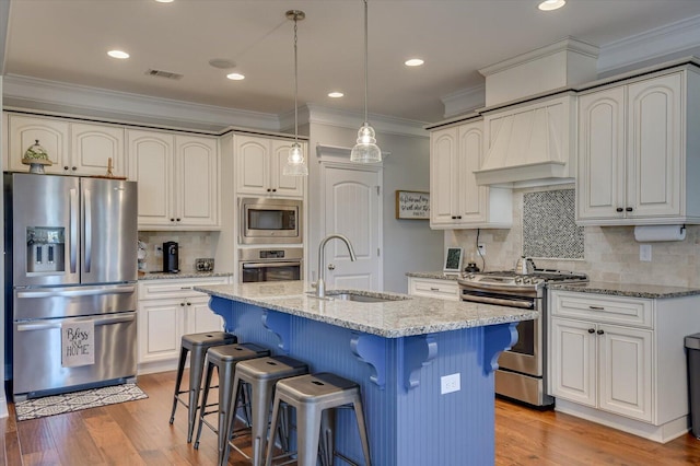 kitchen featuring light stone counters, light wood-style floors, appliances with stainless steel finishes, and a sink