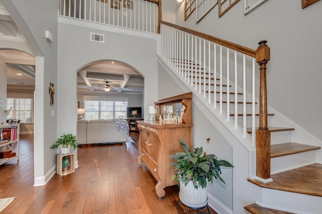 foyer with visible vents, arched walkways, plenty of natural light, and hardwood / wood-style flooring