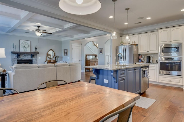 kitchen featuring arched walkways, white cabinetry, stainless steel appliances, and a fireplace