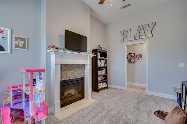 rec room with visible vents, ceiling fan, carpet, a tiled fireplace, and baseboards