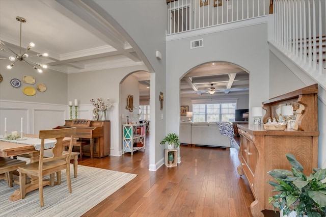 dining space with visible vents, a wainscoted wall, hardwood / wood-style floors, arched walkways, and coffered ceiling