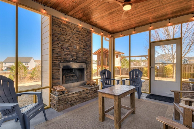 sunroom with ceiling fan, track lighting, wood ceiling, and an outdoor stone fireplace