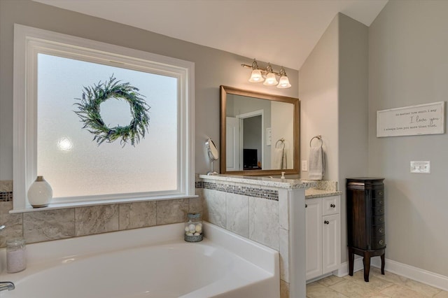 full bathroom with baseboards, vanity, a garden tub, and vaulted ceiling