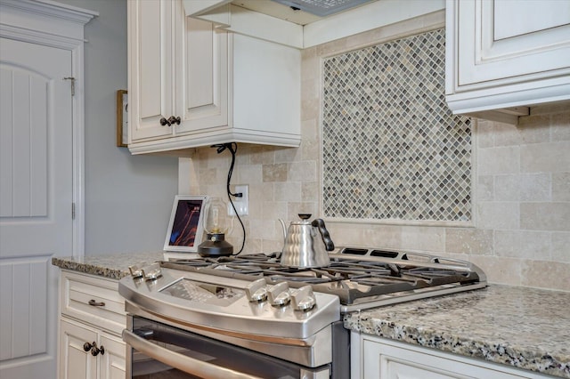 kitchen with backsplash, light stone countertops, and stainless steel range with gas cooktop