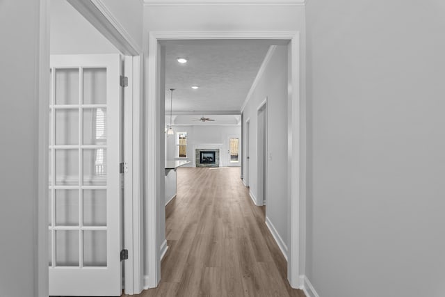 hall with crown molding, a textured ceiling, and light wood-type flooring