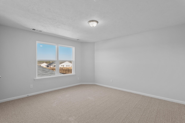 empty room with carpet floors and a textured ceiling