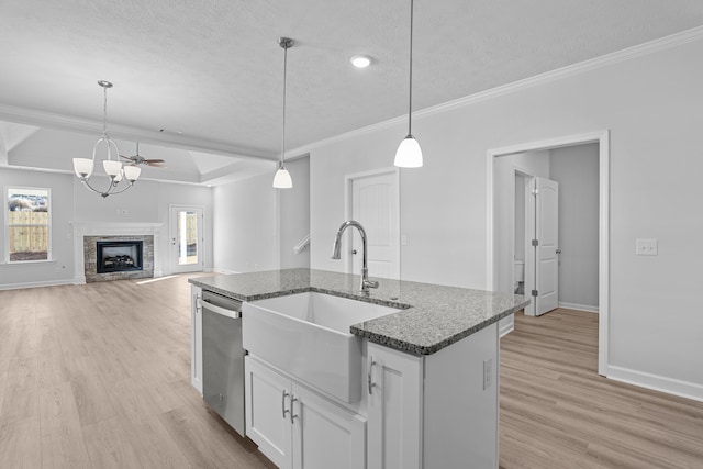 kitchen featuring white cabinetry, sink, stainless steel dishwasher, and decorative light fixtures