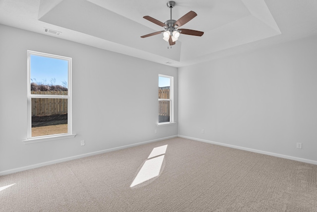 carpeted spare room with ceiling fan and a tray ceiling