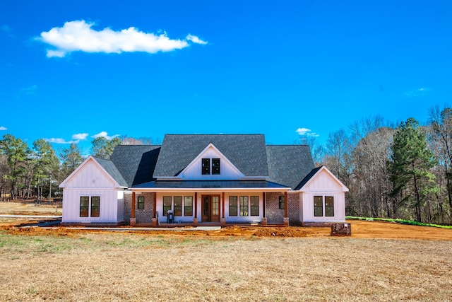 modern inspired farmhouse featuring a porch, board and batten siding, a front lawn, and brick siding