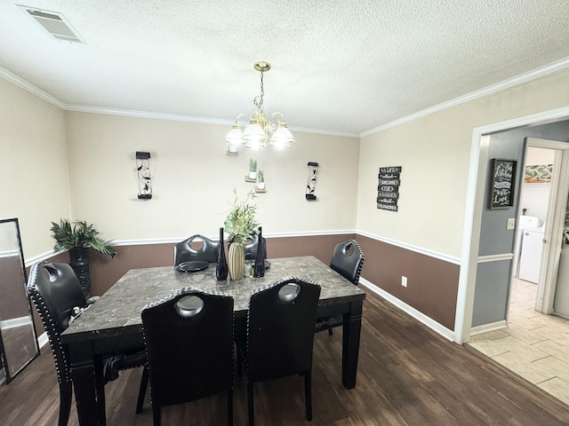 dining room with ornamental molding, dark hardwood / wood-style flooring, an inviting chandelier, and a textured ceiling