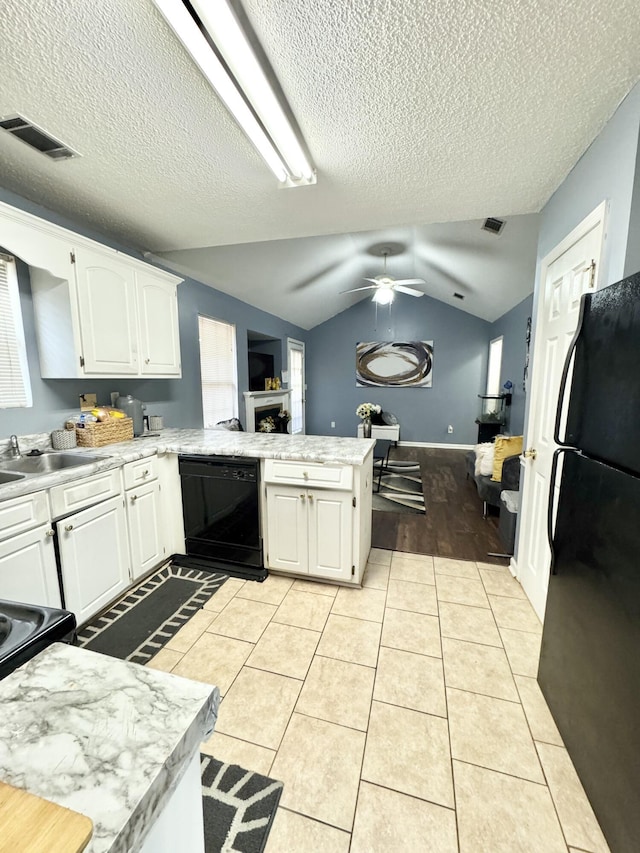 kitchen featuring white cabinets, vaulted ceiling, light tile patterned floors, kitchen peninsula, and black appliances