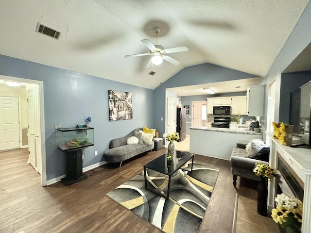 living room featuring a textured ceiling, ceiling fan, vaulted ceiling, and light hardwood / wood-style flooring