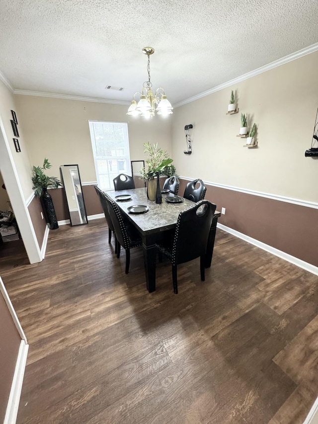 dining room featuring an inviting chandelier, a textured ceiling, crown molding, and dark wood-type flooring