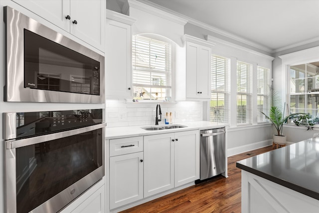 1037 Bartram Rdg, Evans, GA 30809 - kitchen with appliances with stainless steel finishes, dark wood-style flooring, ornamental molding, white cabinetry, and backsplash