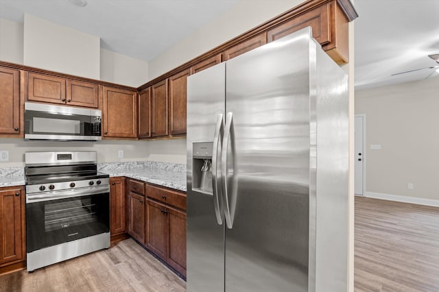 502 Shadowmoor Ct, Thomson, GA 30824 - kitchen with stainless steel appliances, light wood-type flooring, light stone counters, ceiling fan, and brown cabinets