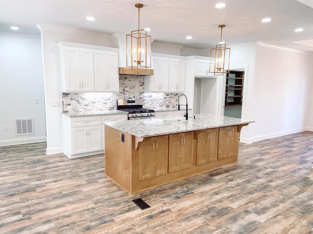 kitchen with stainless steel gas range, visible vents, light wood-style floors, and crown molding