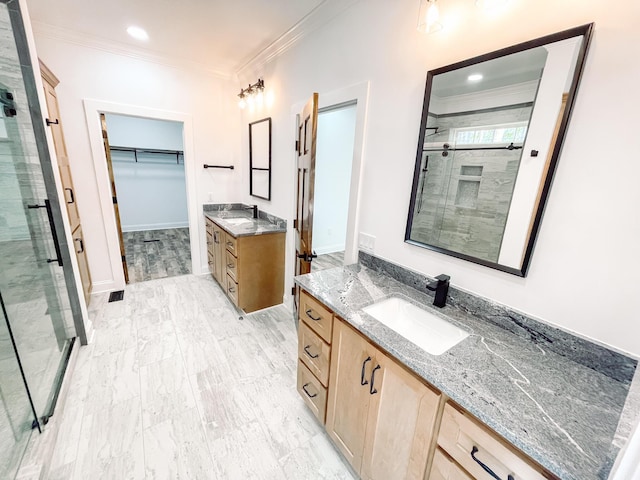 full bath with two vanities, a sink, ornamental molding, a shower stall, and a walk in closet